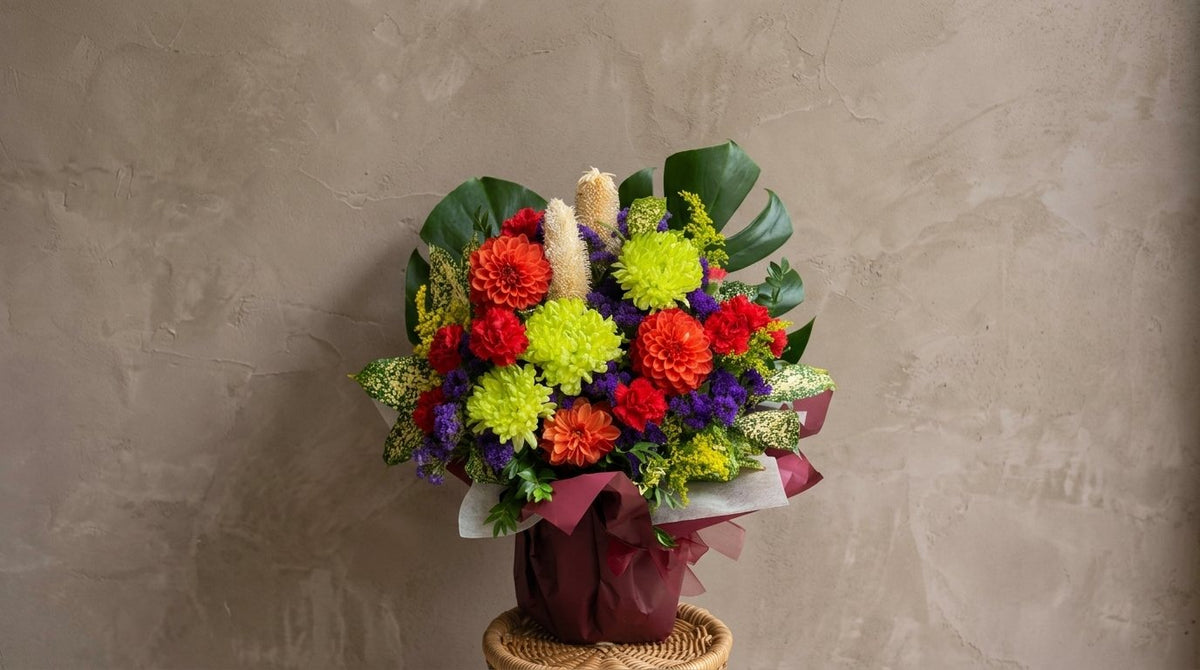 Green and orange chrysanthemum arrangement with purple statice in a woven basket, a Mid-Autumn Festival gift from H Flowers Melbourne